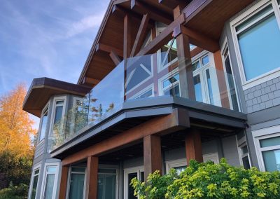 Photo of the exterior of a home with a second floor deck featuring frameless glass railings.