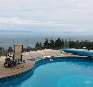 J.R.E. Hardware Glacier Lite glass panels used in a frameless glass railing pool surround overlooking the ocean.
